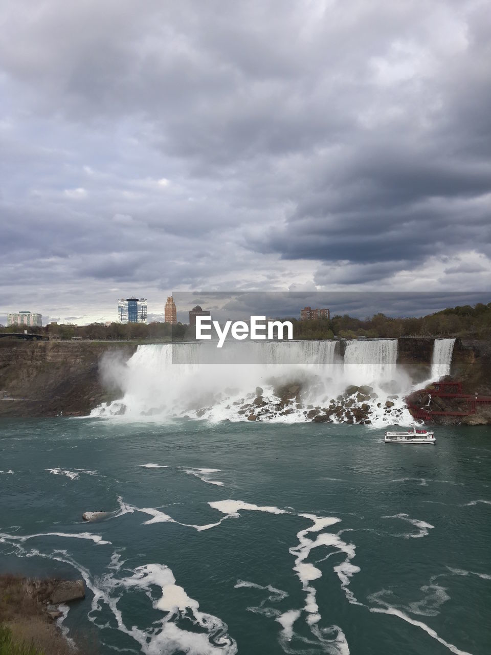 Scenic view of waterfall against cloudy sky