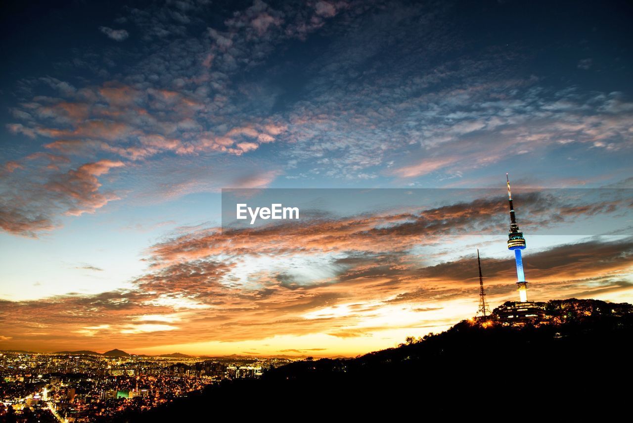 Illuminated cityscape against scenic sky