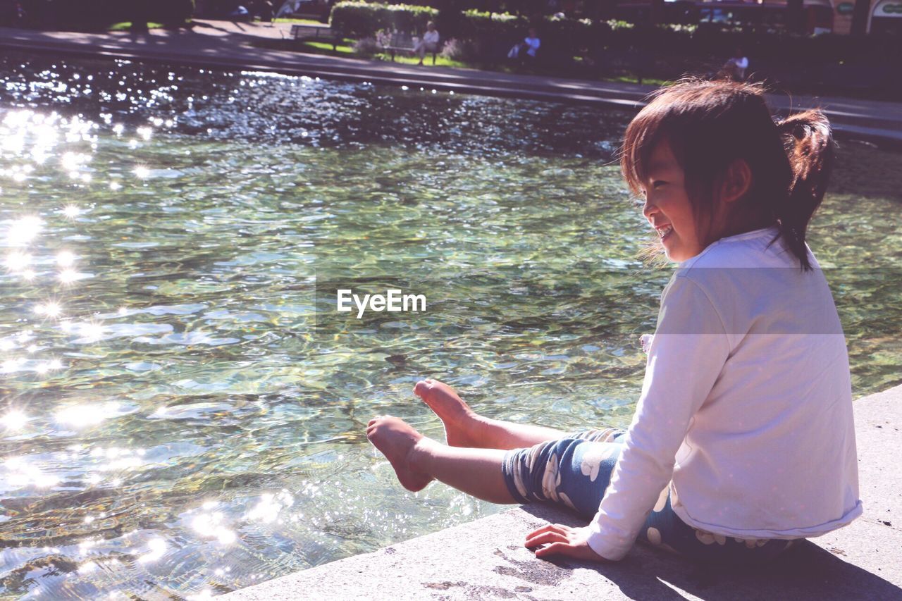 Girl sitting by swimming pool