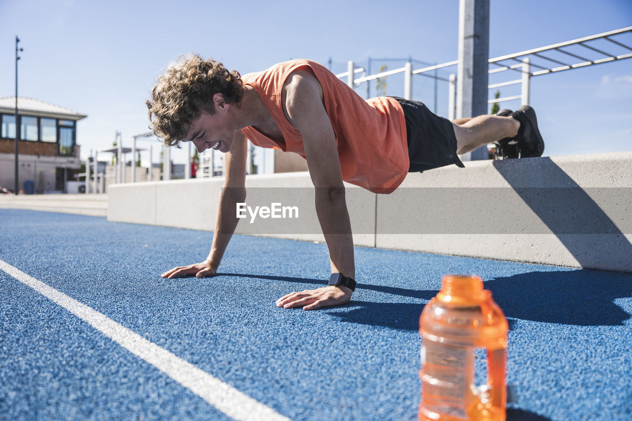 Happy sportsman doing push-ups on running track