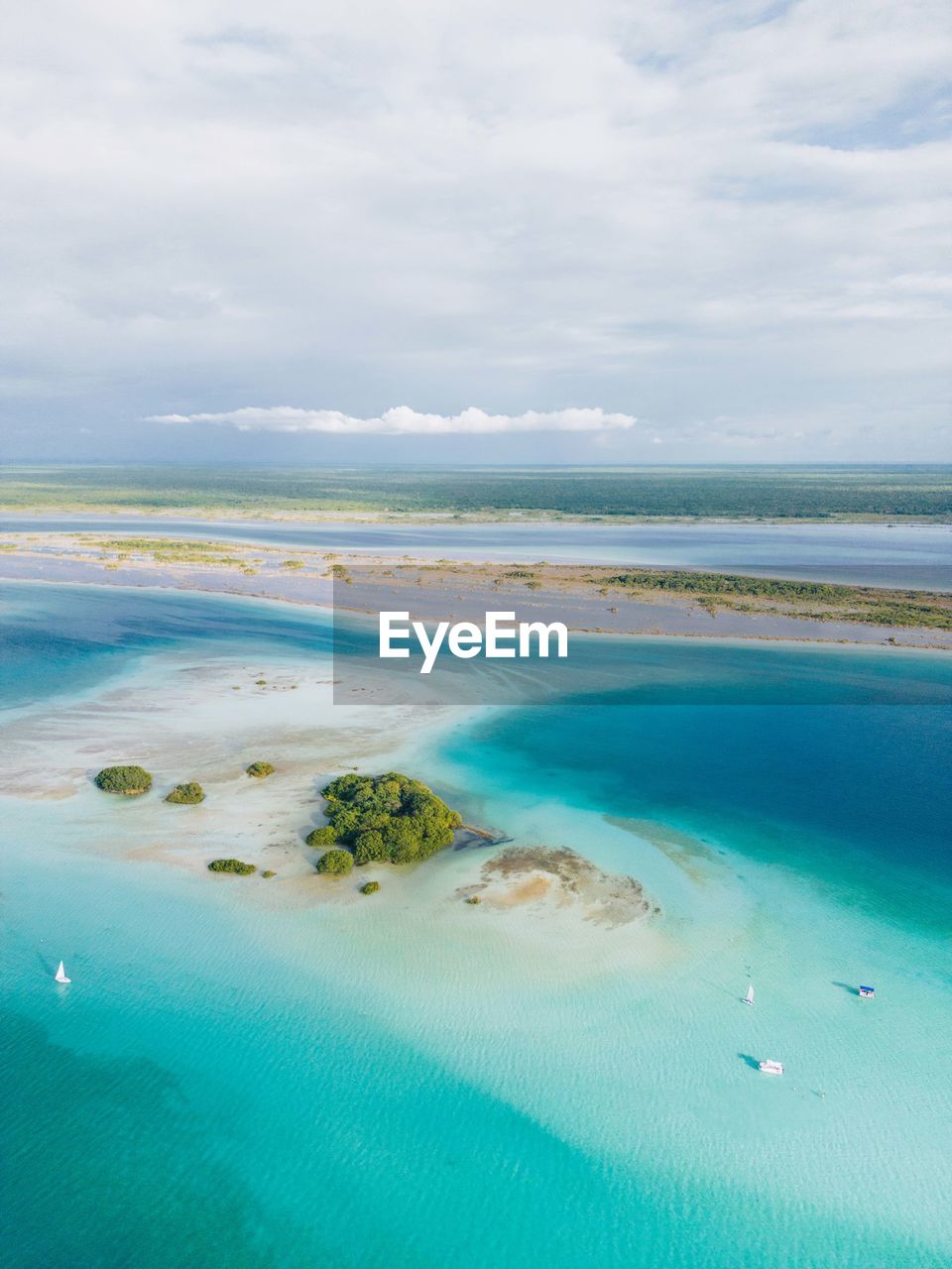 Drone view of a blue lagoon with some boats and an island