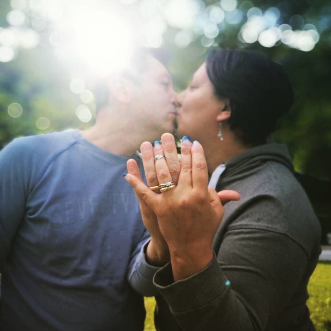 Close-up of mature couple showing wedding rings while kissing at park