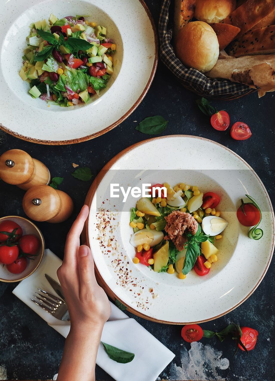 Close-up of hand holding food in plate on table