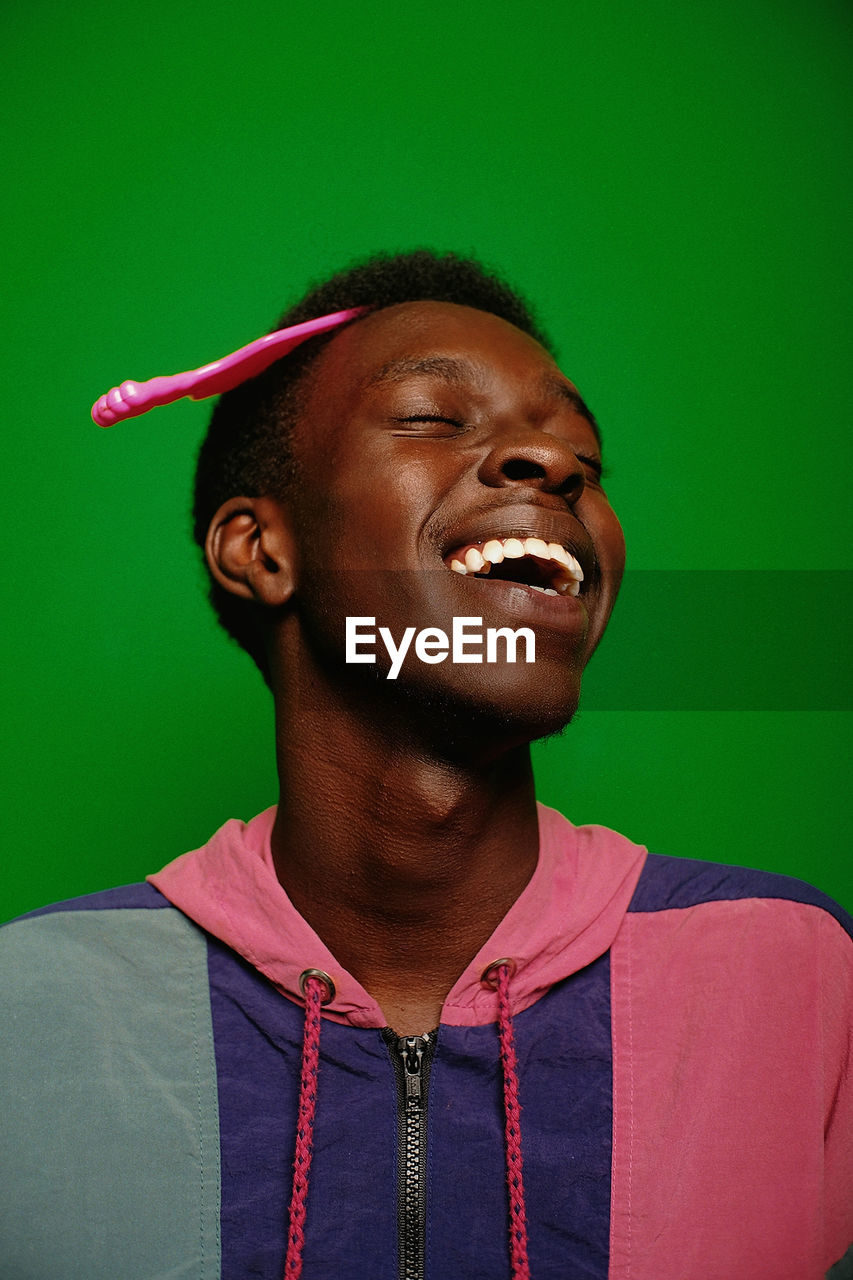 Smiling man with comb in hair against green background