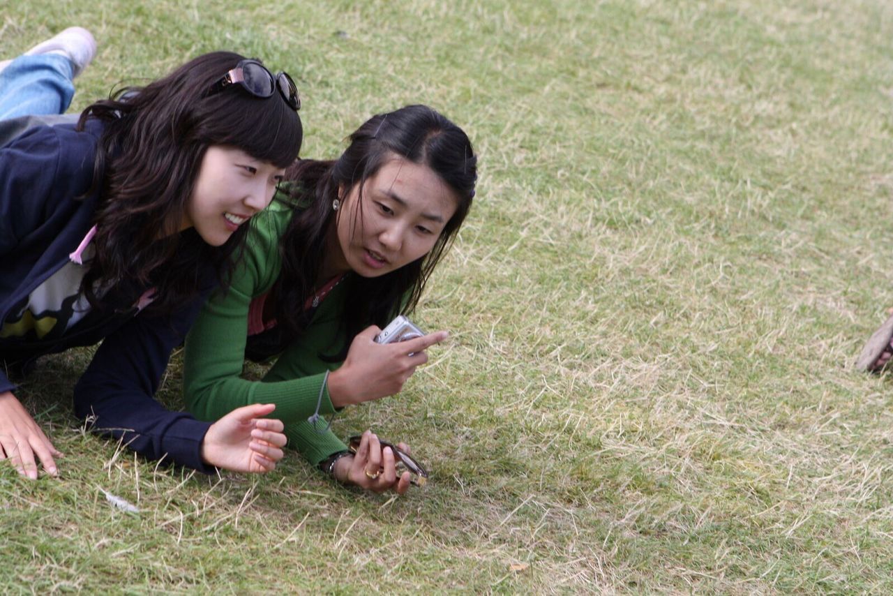 PORTRAIT OF SMILING GIRL ON GRASSY FIELD