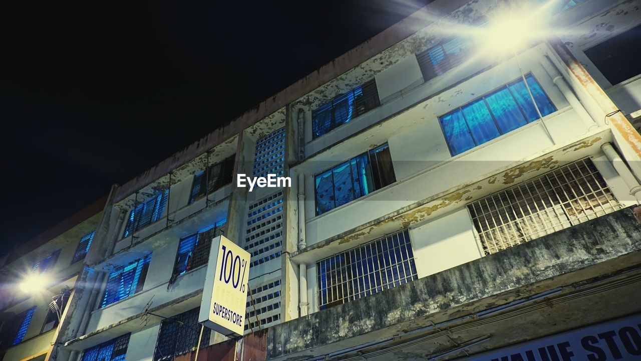 LOW ANGLE VIEW OF ILLUMINATED BUILDINGS AT NIGHT