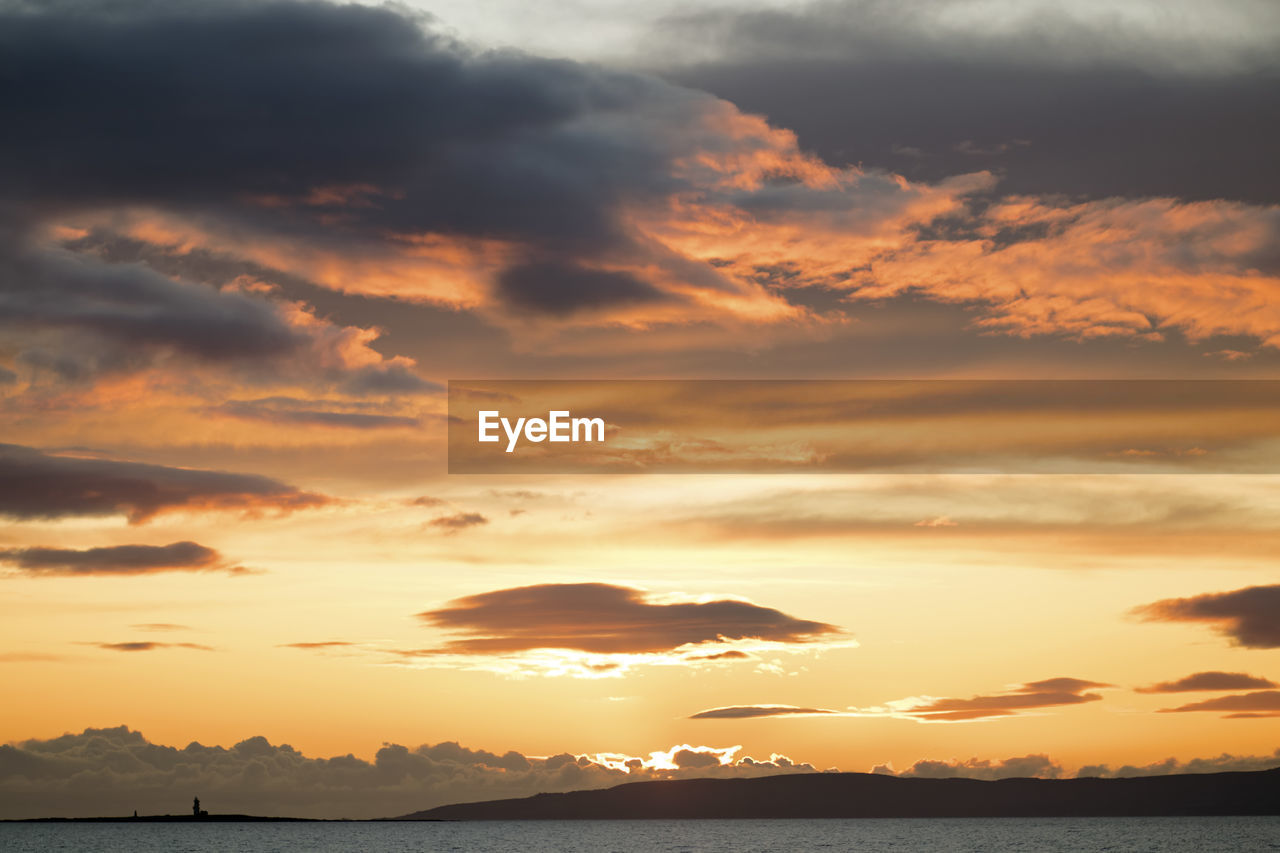 Scenic view of sea against dramatic sky during sunset