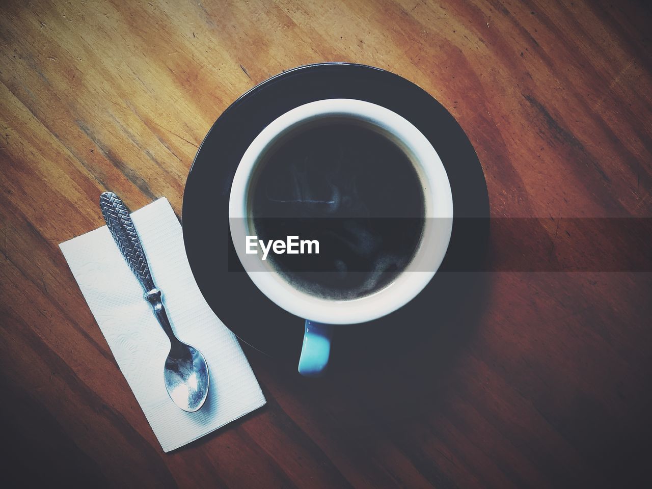 HIGH ANGLE VIEW OF COFFEE CUP ON WOODEN TABLE