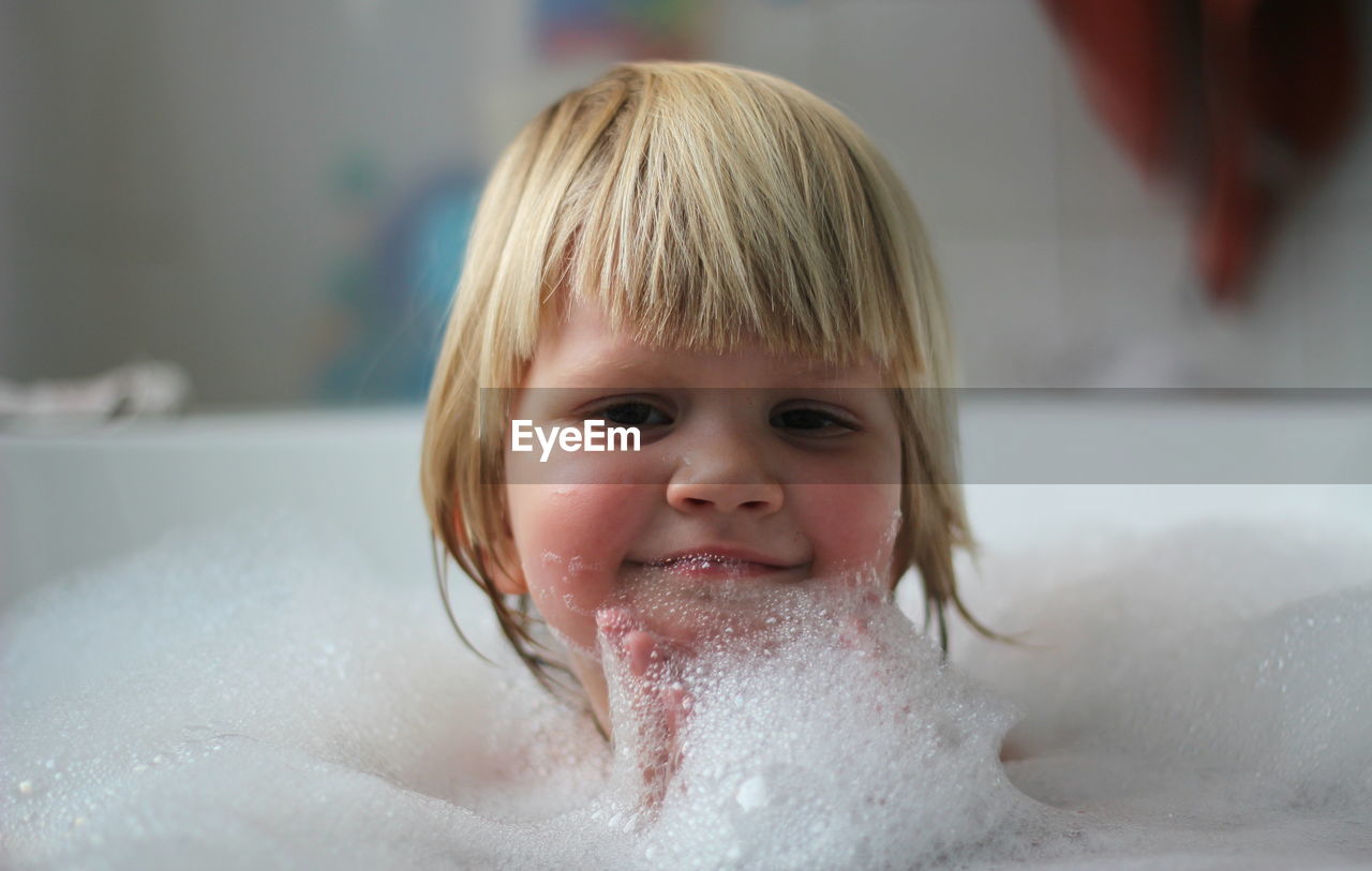 Close-up portrait of a smiling boy in bathtub
