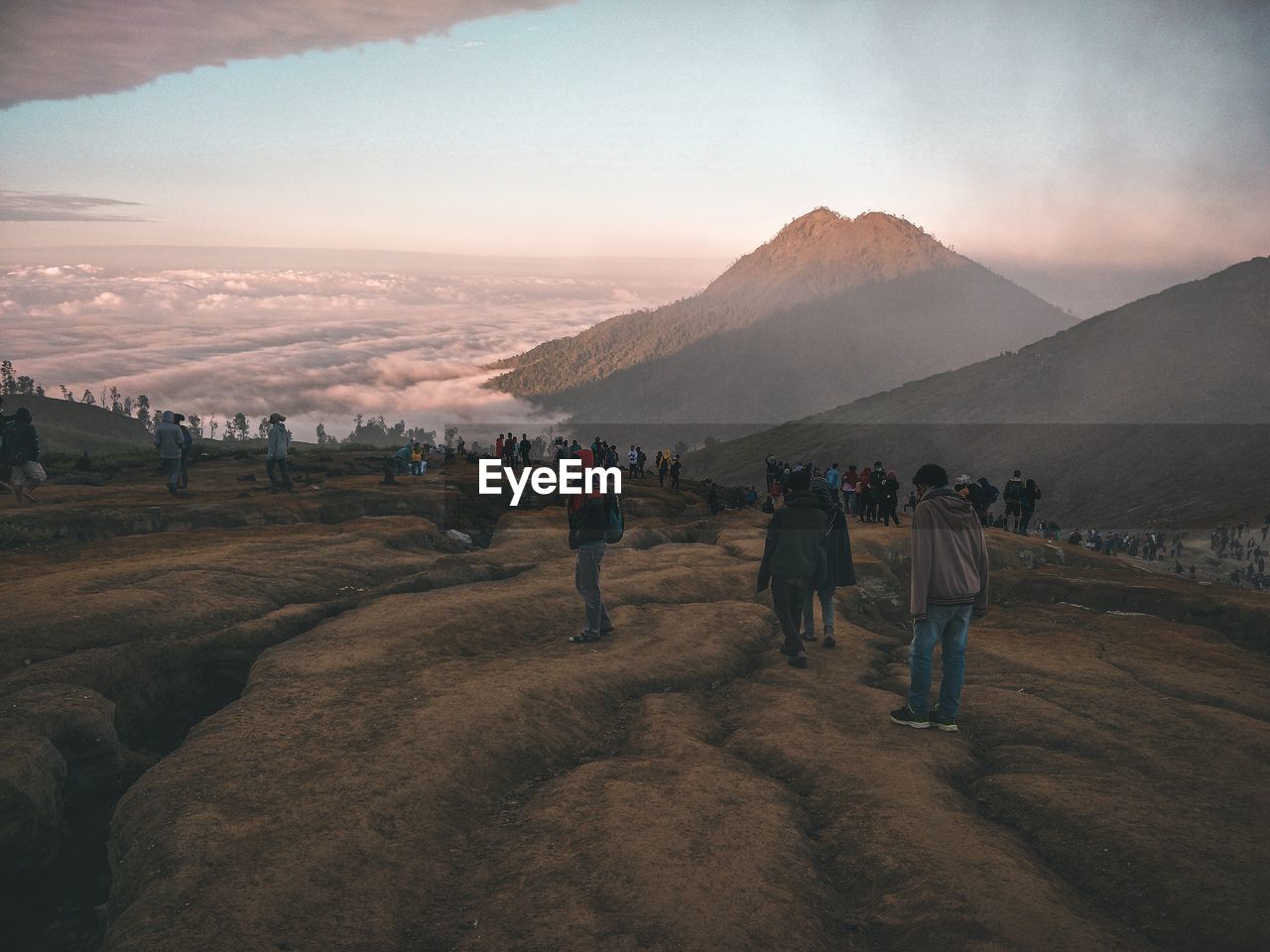 REAR VIEW OF PEOPLE WALKING ON LAND AGAINST MOUNTAINS