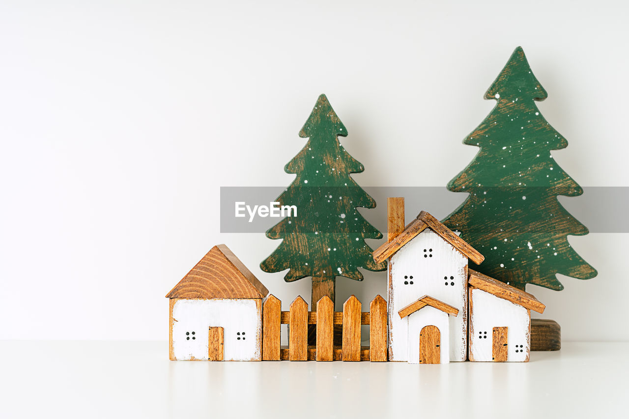 Happy new year and merry christmas postcard. white background with toy wooden house, snow,  tree