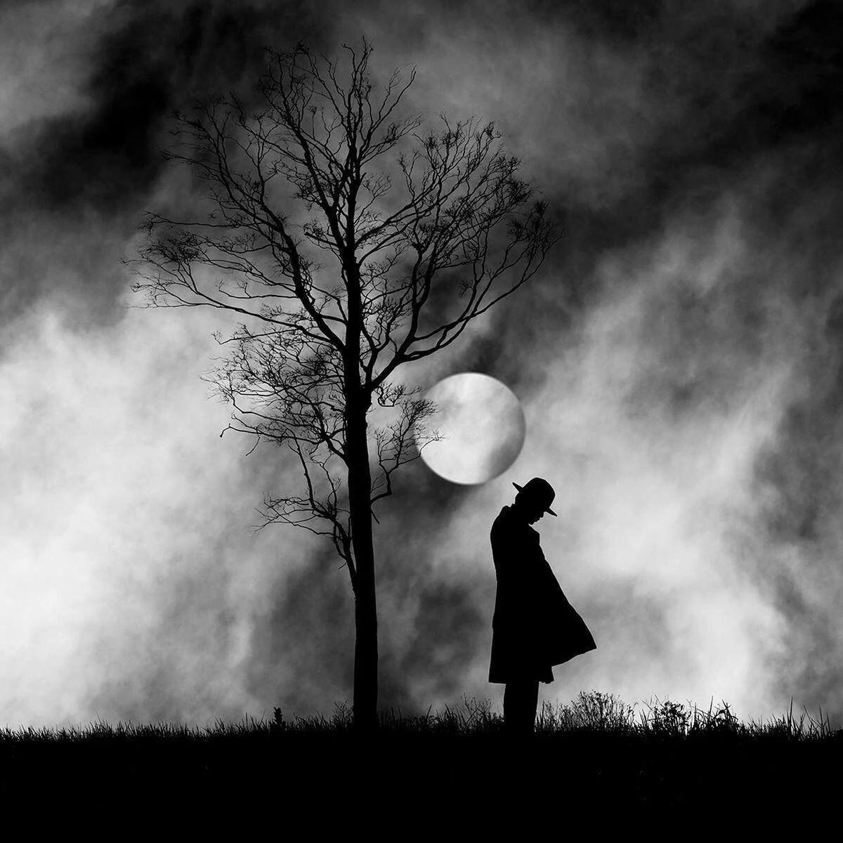 Man standing by tree against moon at night