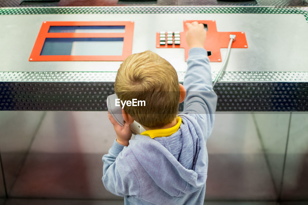 High angle view of boy using pay phone