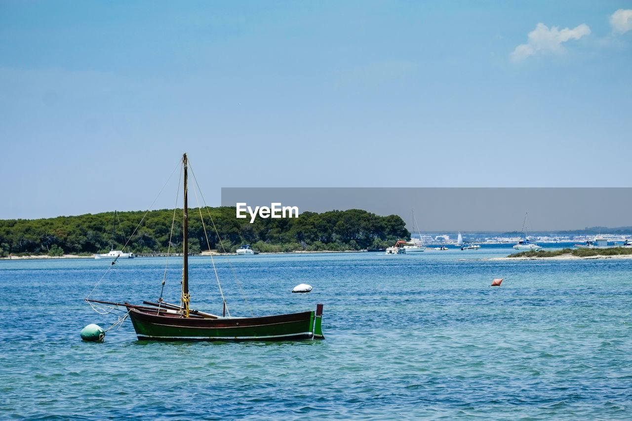 Boat sailing in sea against clear blue sky