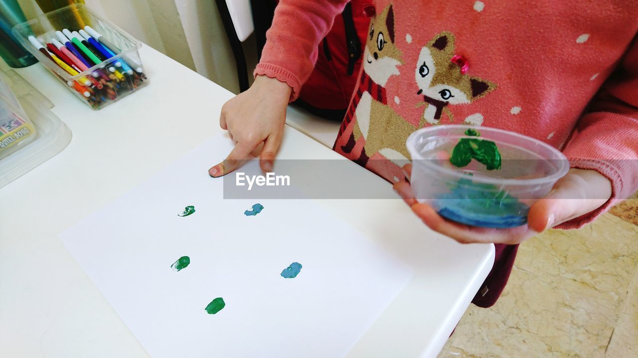 Midsection of boy painting on paper at table