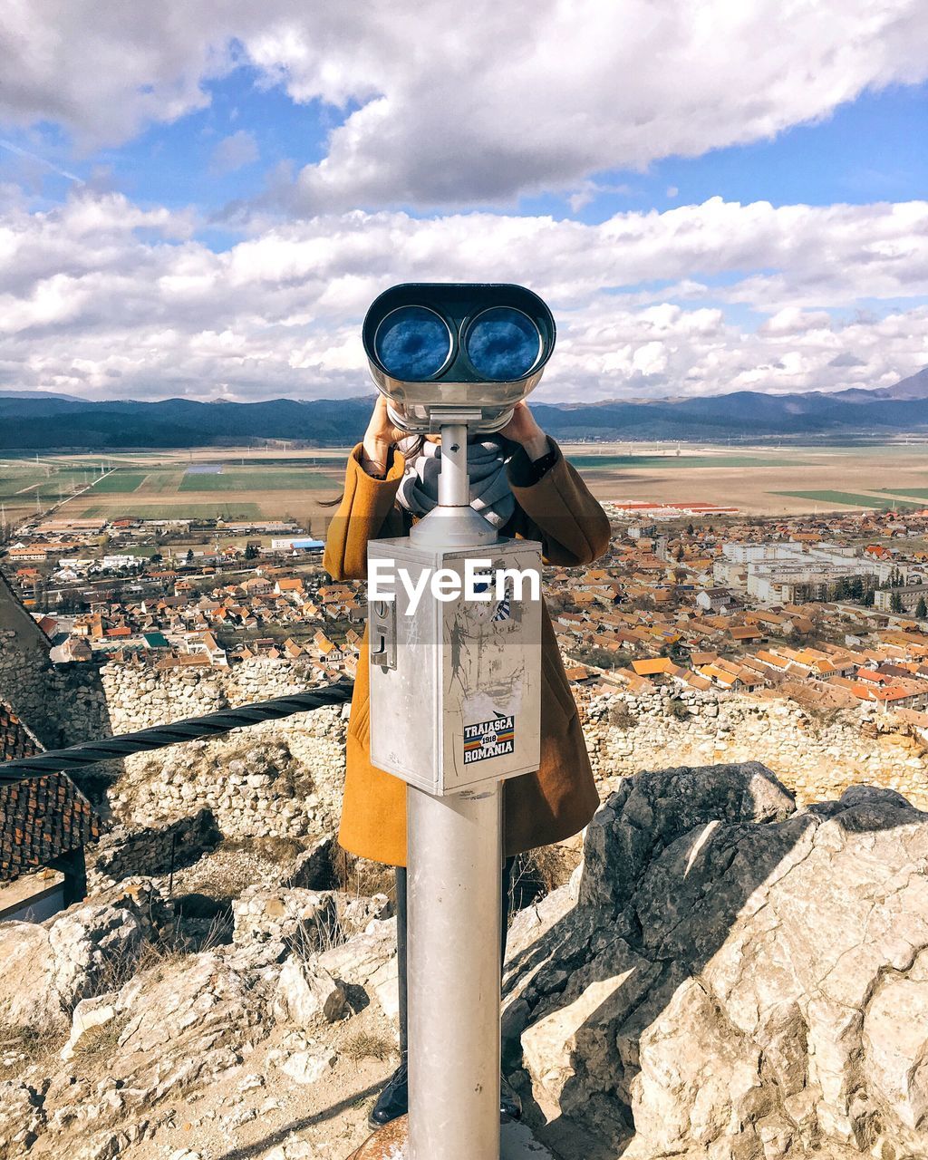 Woman looking through coin-operated binoculars on cliff