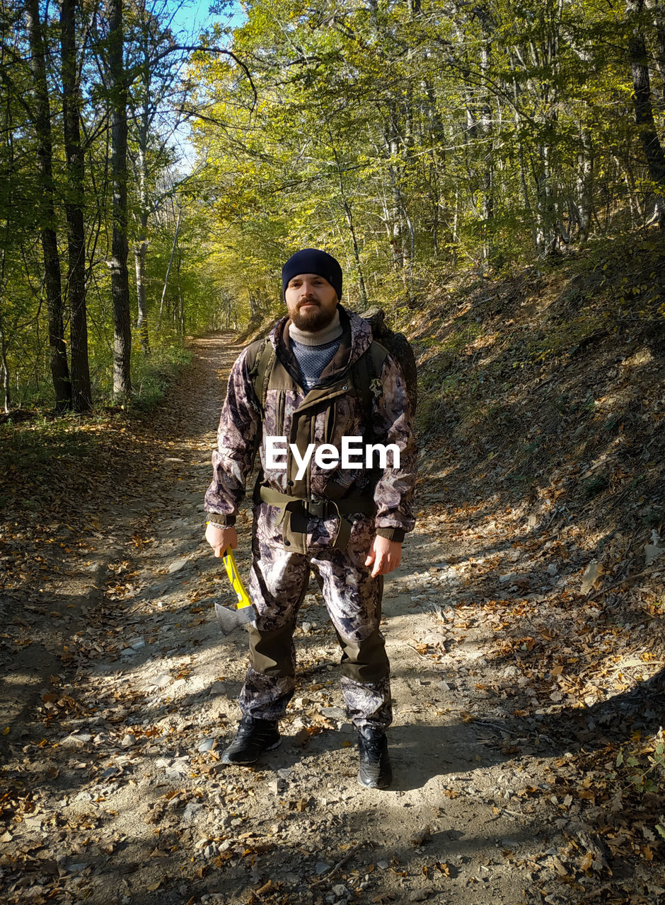 Full length portrait of young man standing in forest