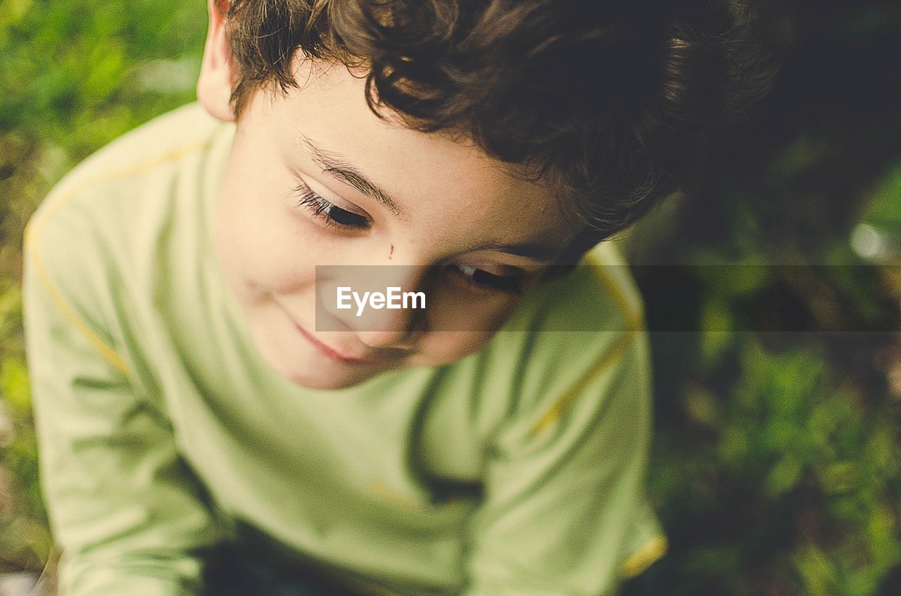 High angle close-up of thoughtful boy looking away while sitting outdoors