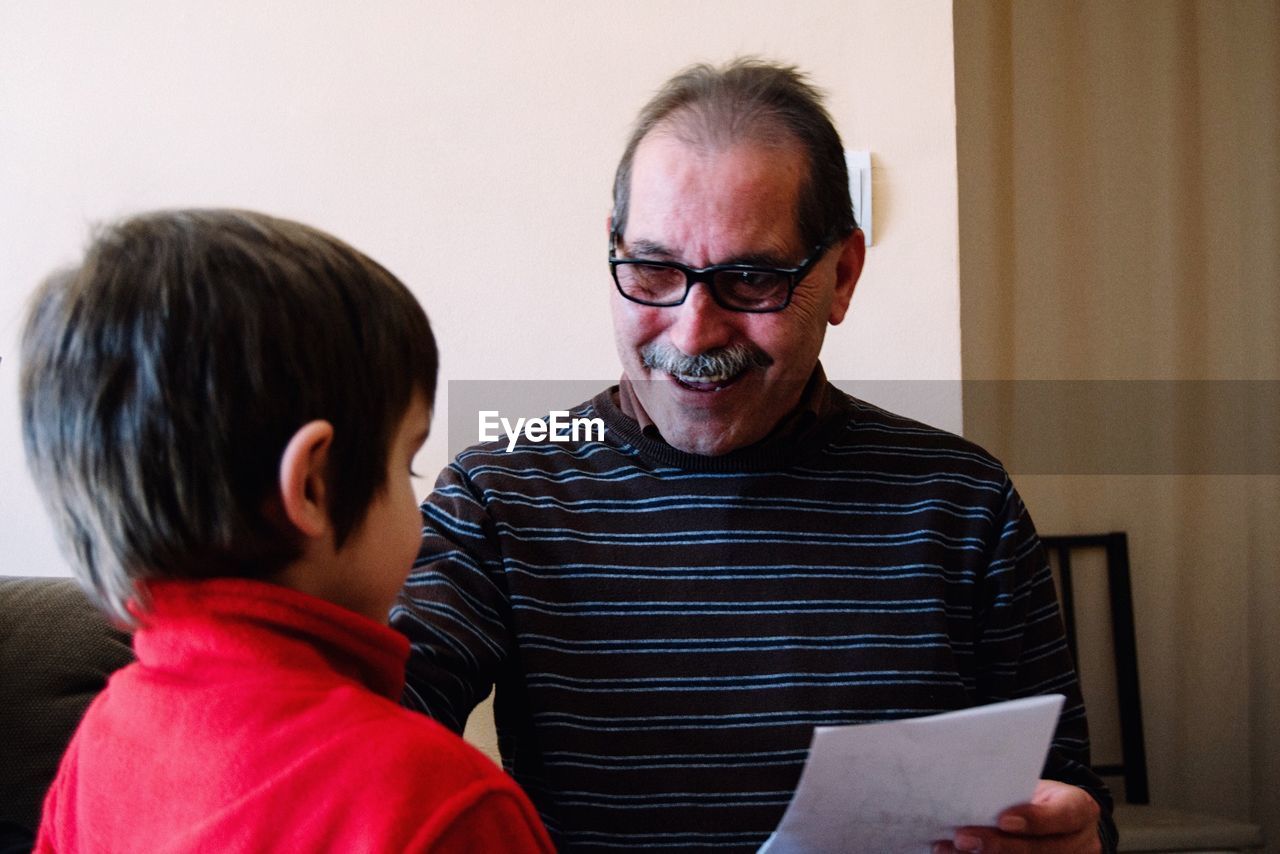 Happy grandfather looking towards grandson in house