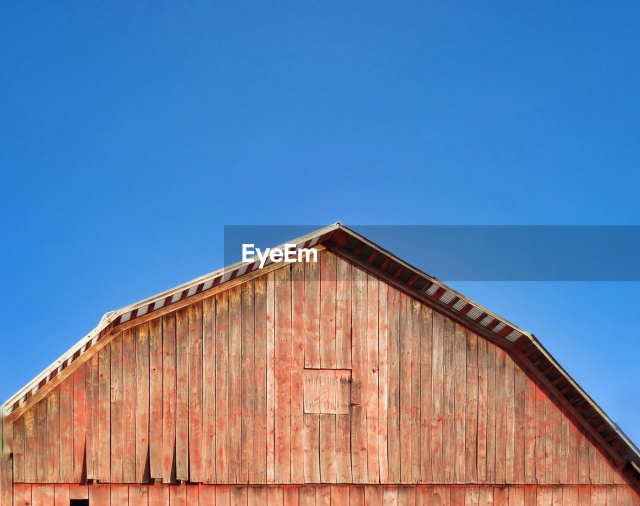 Low angle view of old red building against clear blue sky