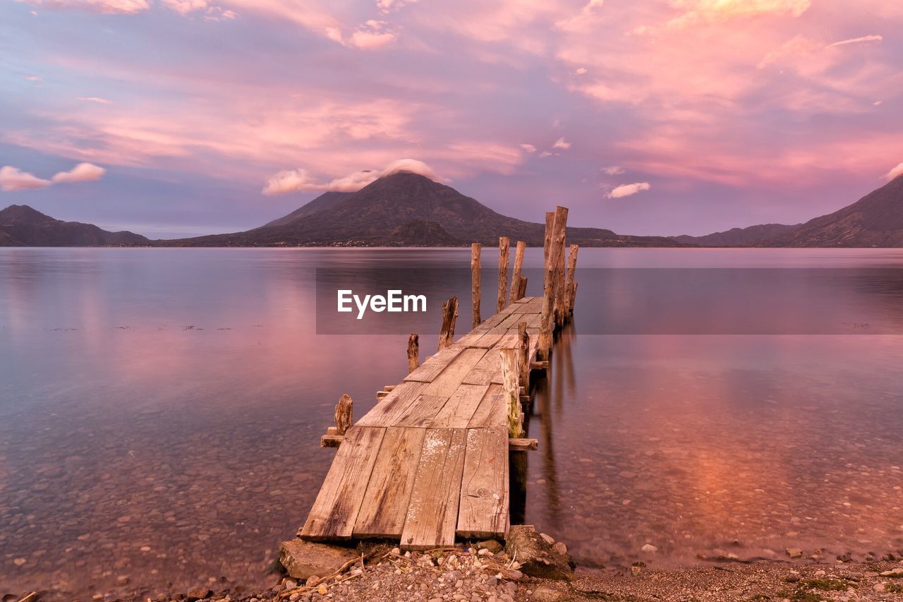 Pier over lake against sky during sunset