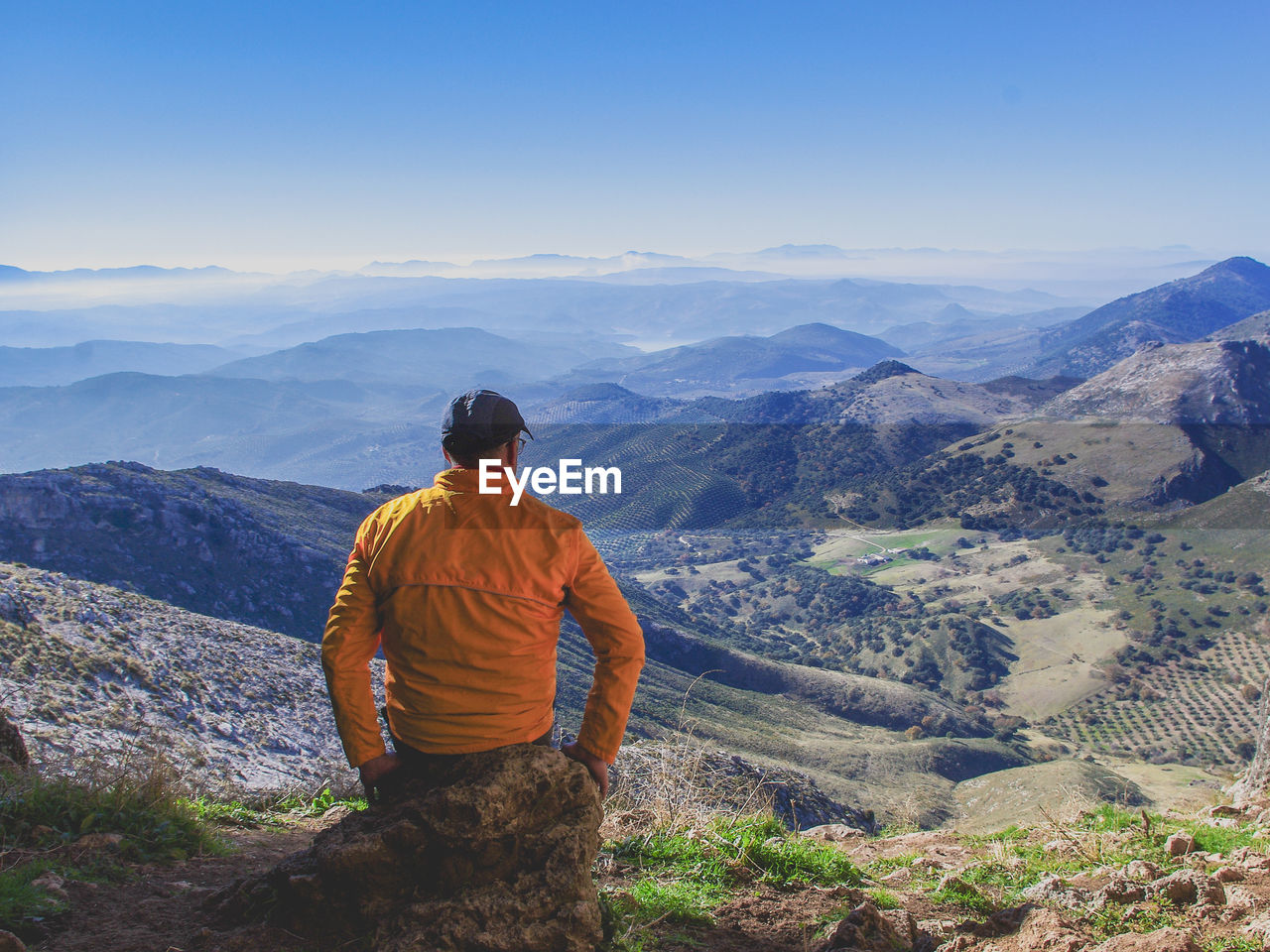 Rear view of man standing on mountain against sky