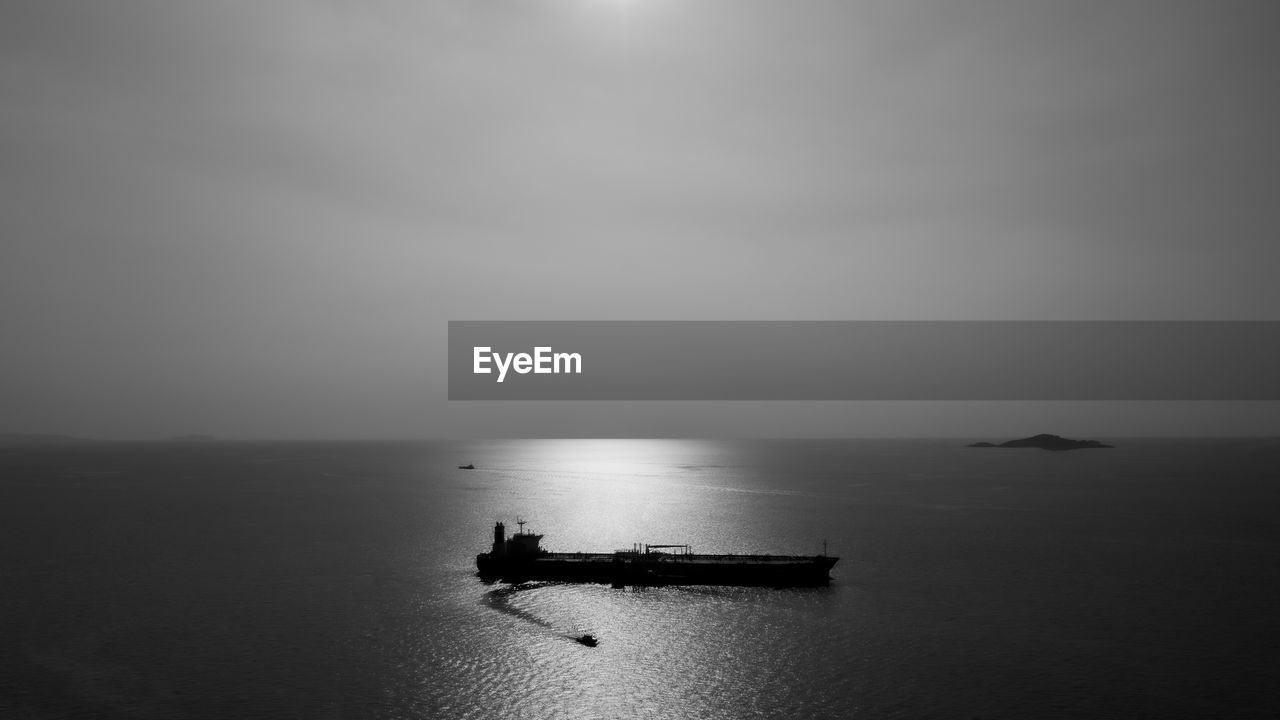 Black and white silhouette shipping oil float in sea aerial view horizon background