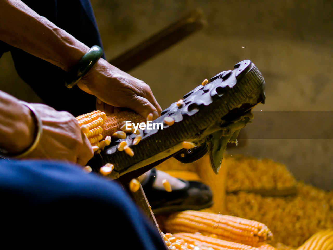 Cropped hands of man removing corn kernels in workshop