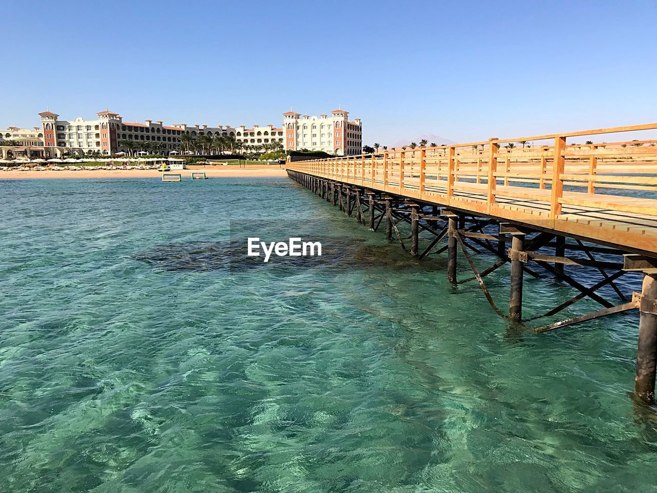 BRIDGE OVER SEA BY BUILDINGS AGAINST CLEAR SKY