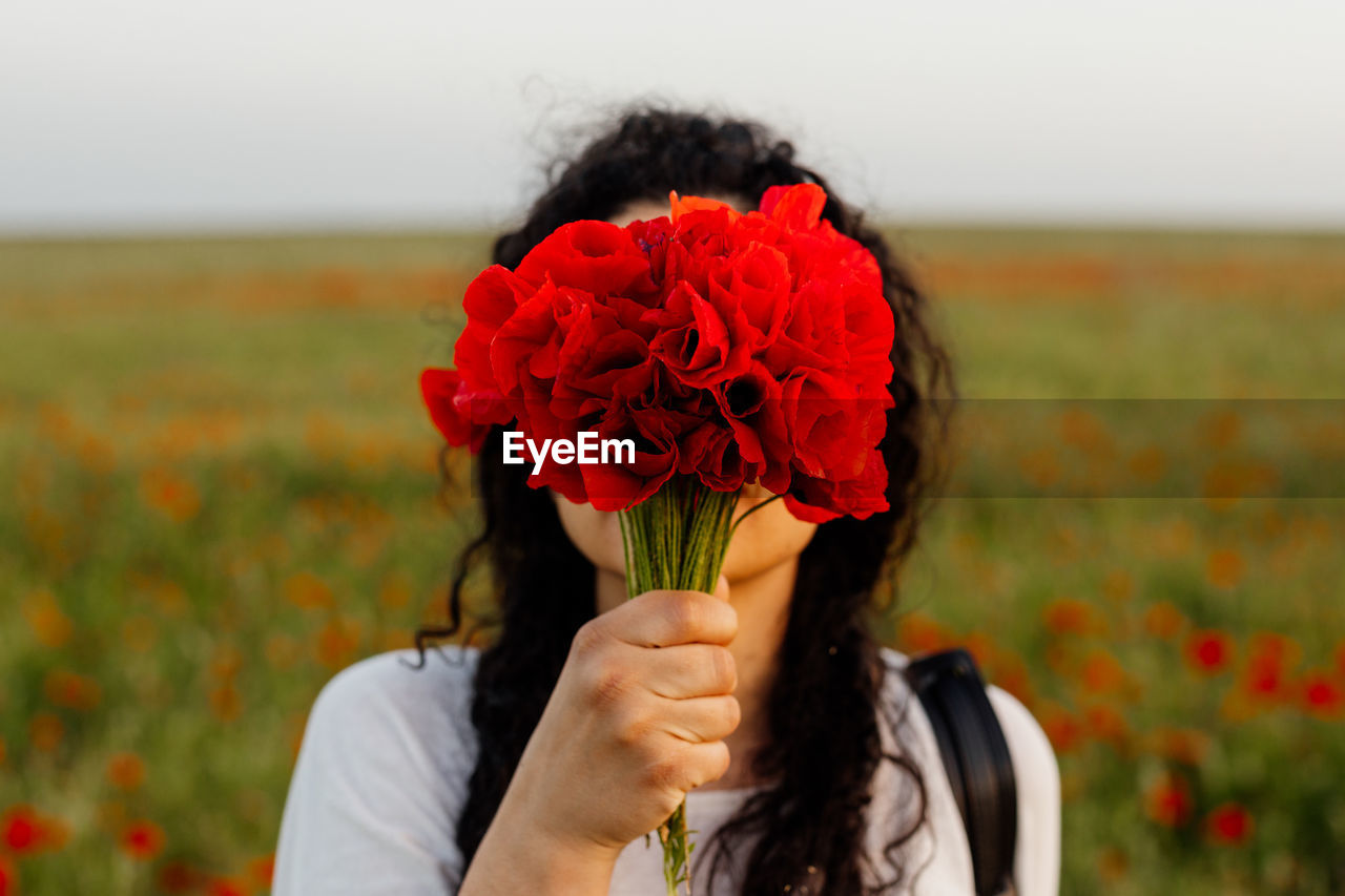 Woman with poppy bouquet covering face