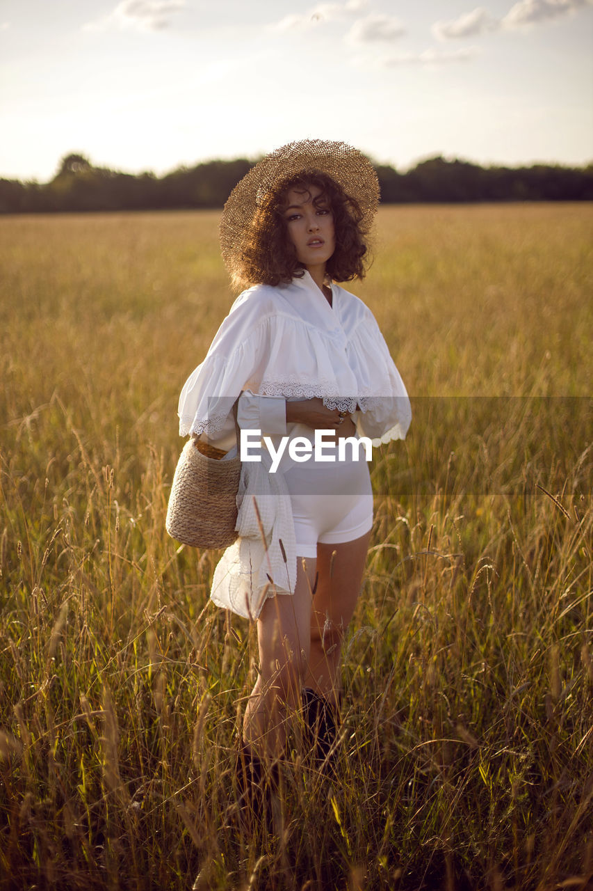  portrait of a curly-haired woman in white clothes and in a wicker hat and with a basket in autumn