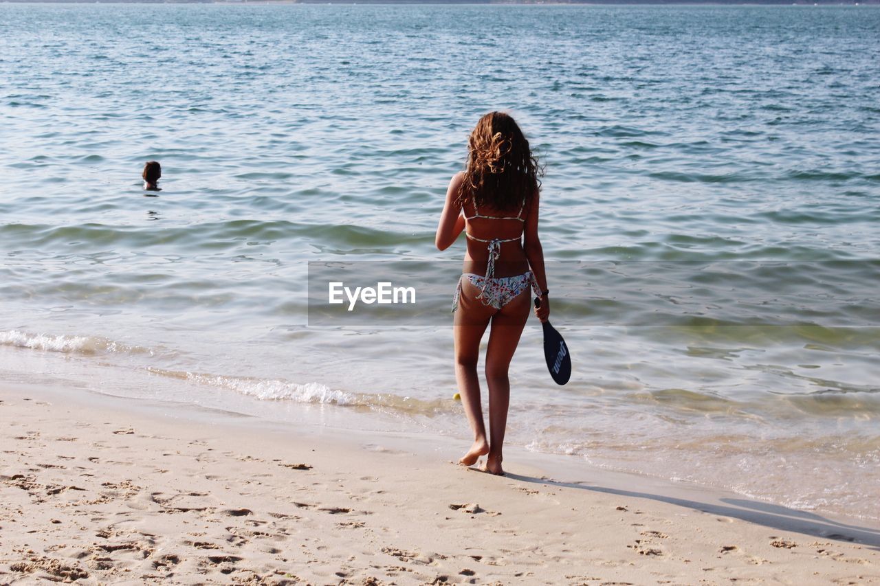 Rear view full length of woman walking on shore at beach