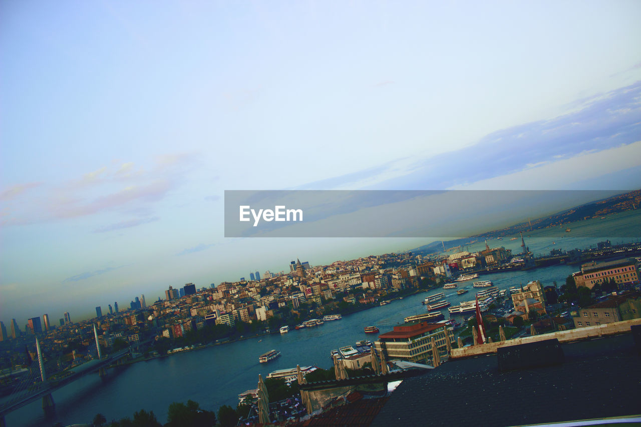 HIGH ANGLE VIEW OF SEA AND CITY BUILDINGS AGAINST SKY