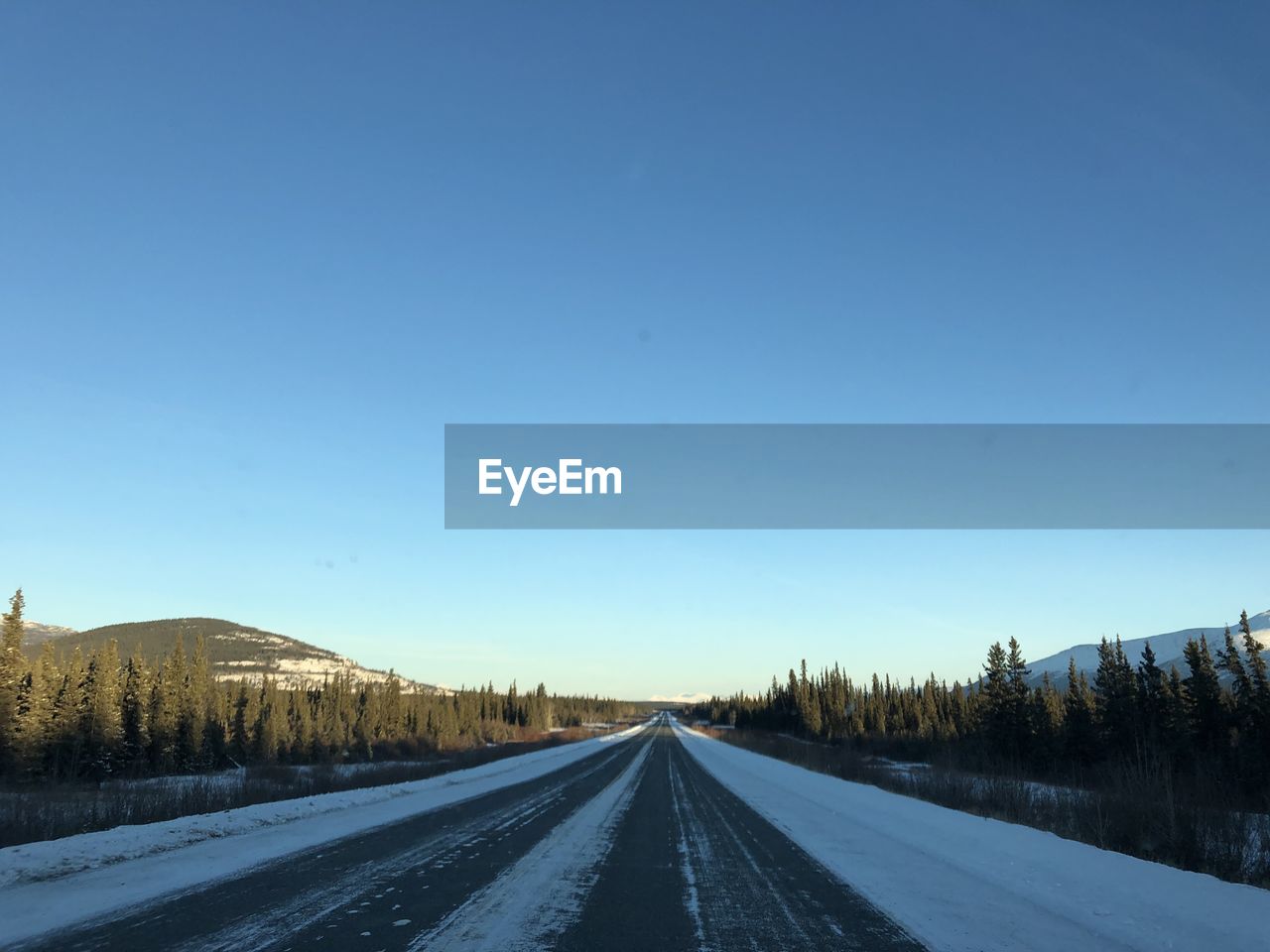 Road against clear blue sky during winter