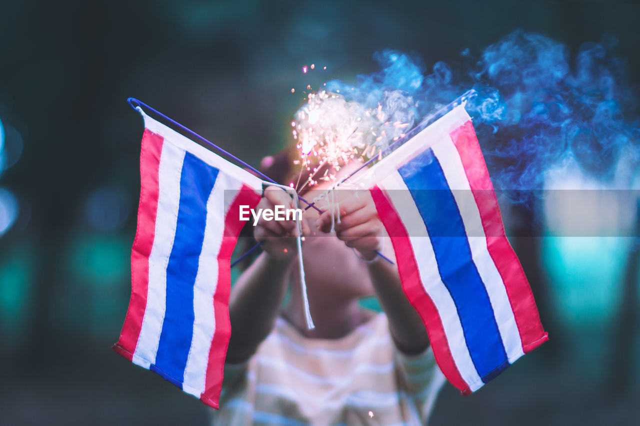 Girl holding sparkler with thai flags during celebration event