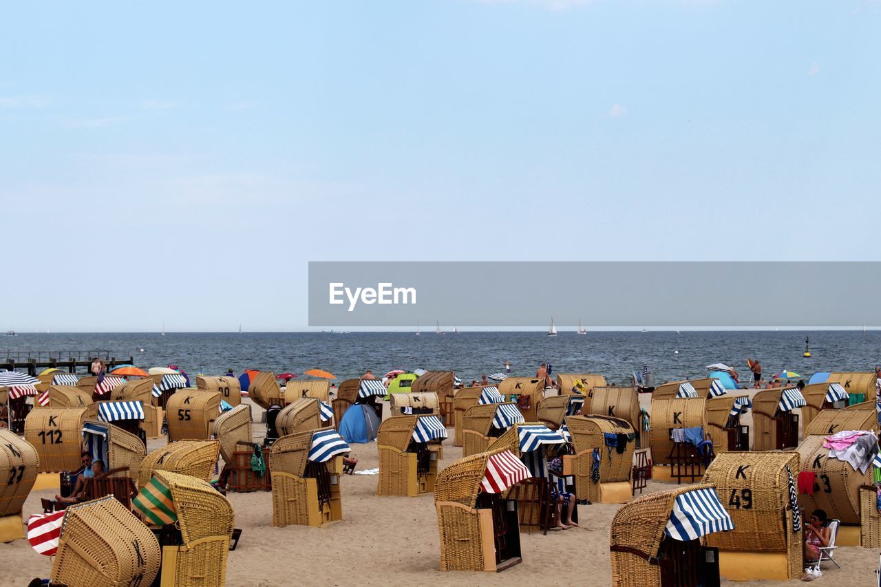 Hooded chairs at beach against clear sky