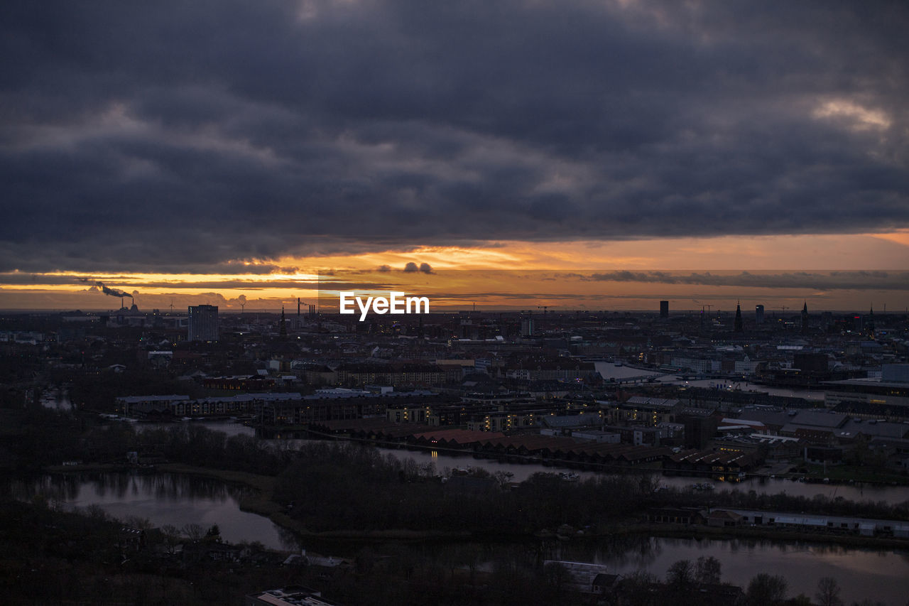 Aerial view of city buildings against sky at sunset