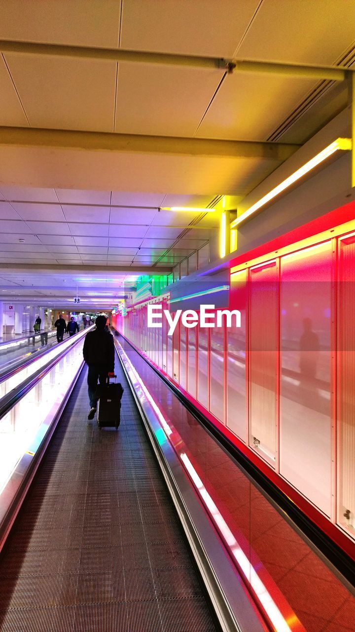 Rear view of man on moving walkway in airport