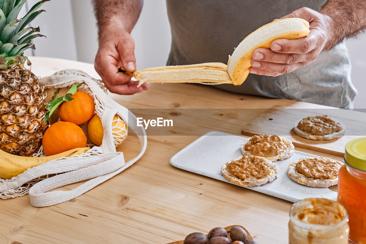 Man preparing healthy organic breakfast with puffed corn cakes, peanut butter and banana.