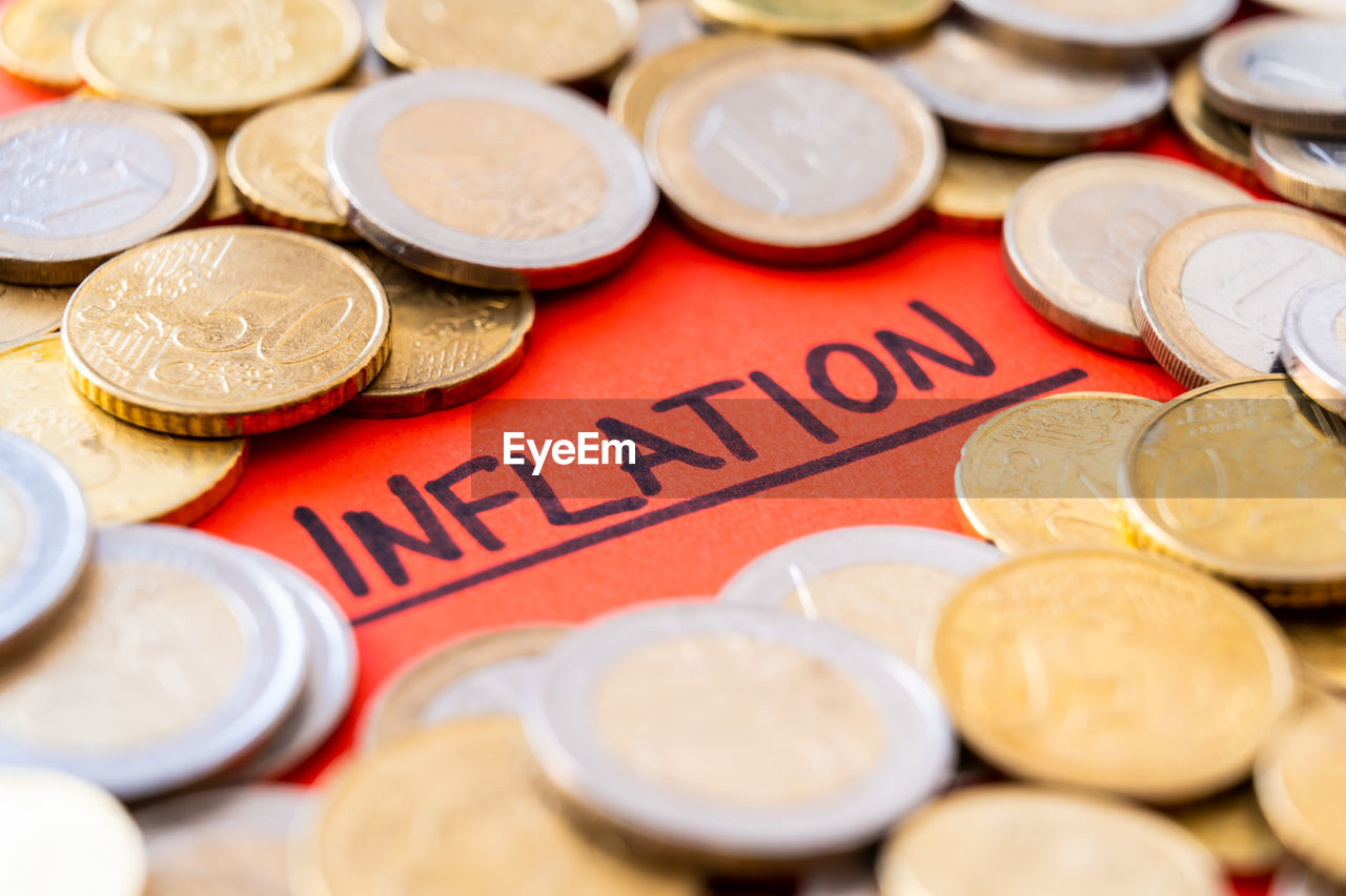 Word inflation on red surface, surrounded by euro coins. rising prices, economic repercussions.