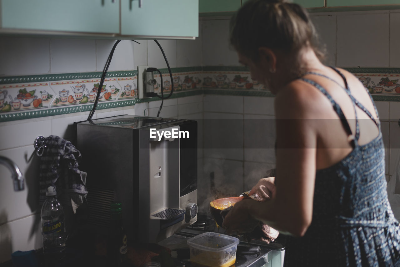 Caucasian woman with her back to her cooking in the kitchen.