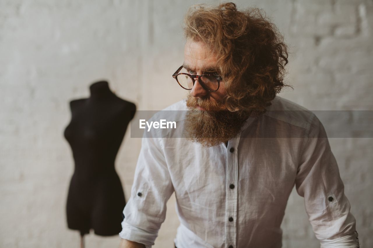 Fashion designer looking away against mannequin