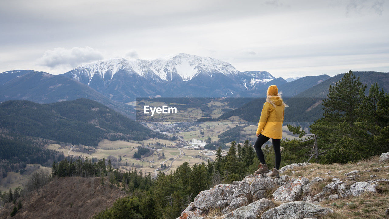 Female hiker on the top of the mountain enjoying the view on snowy peak in background, austrian alps