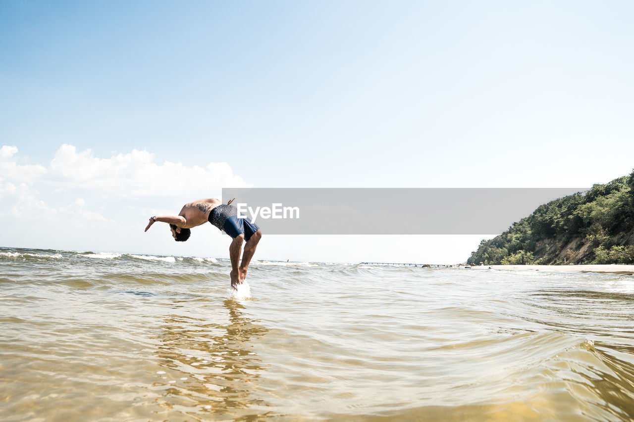 Full length of man diving in sea against sky