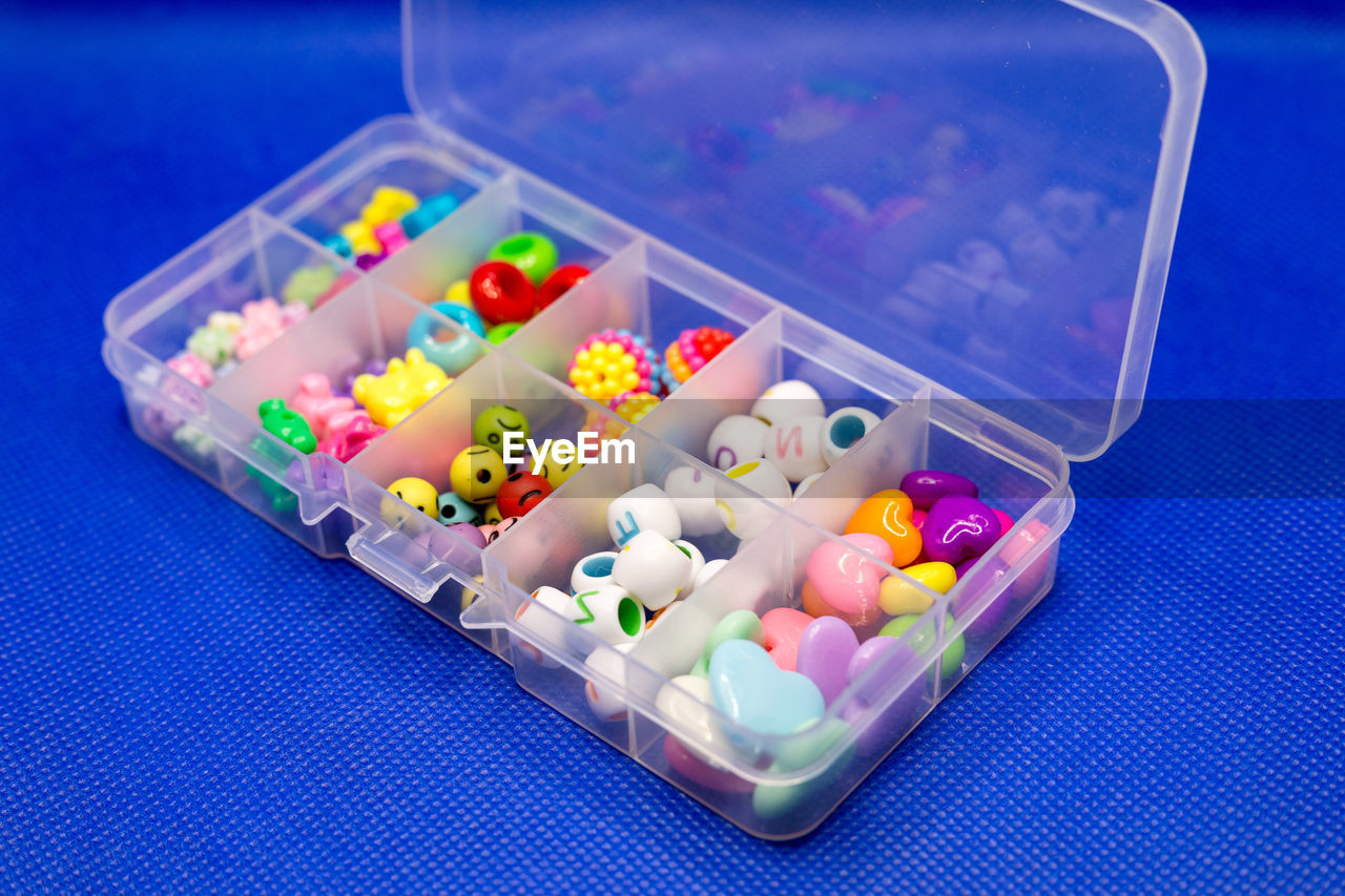 Plastic container with colored round buttons, jewelry clothes in separate cells.