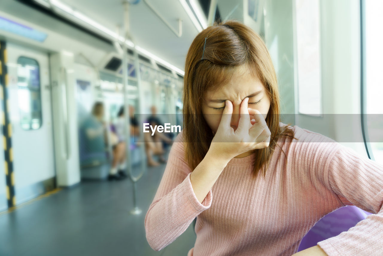 Woman with headache sitting in train