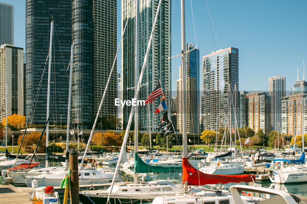 Boats moored in marina by modern skyscrapers