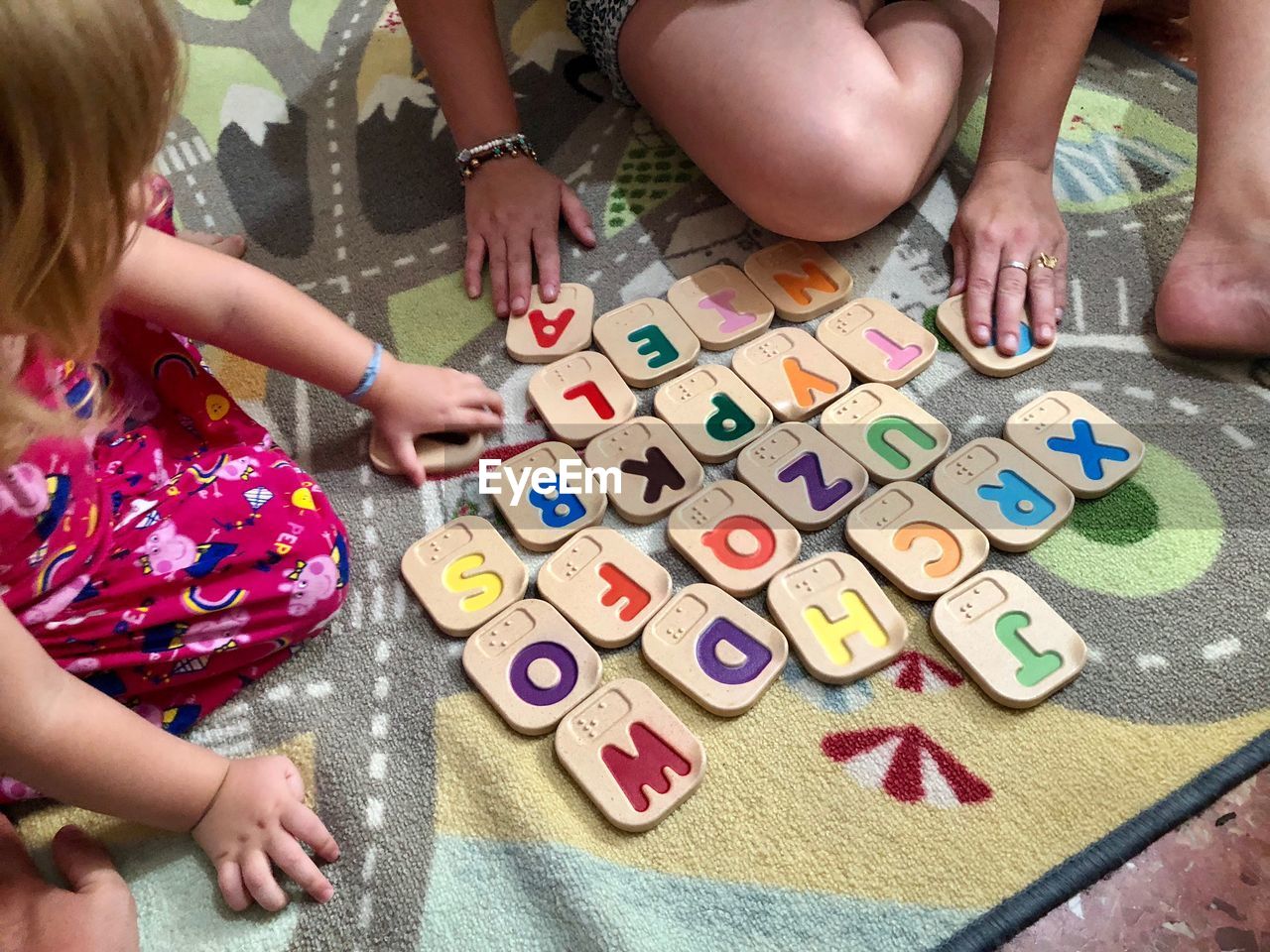 High angle view of mother and daughter playing with alphabets at home