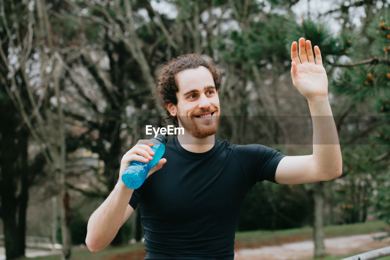 Smiling man gesturing while standing outdoors