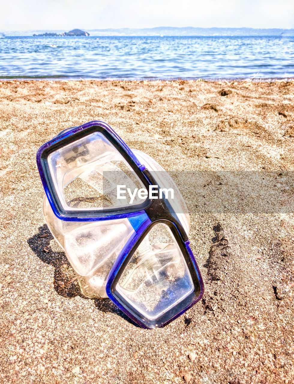 Mask on sand at beach against sky